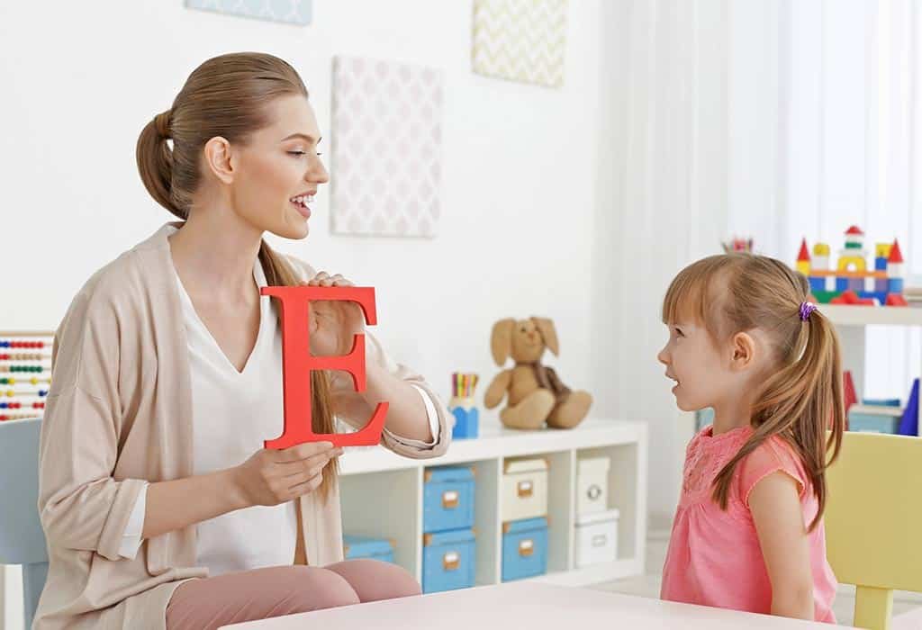 Teacher helping a child learn letter sounds during a phonics reading lesson